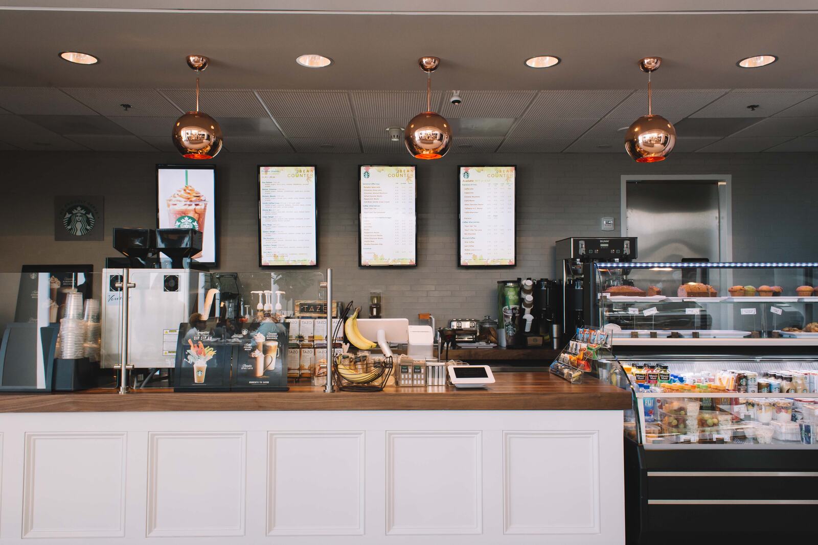 Inside The Bean Counter — copper pendants over a white counter and butcher-block bar