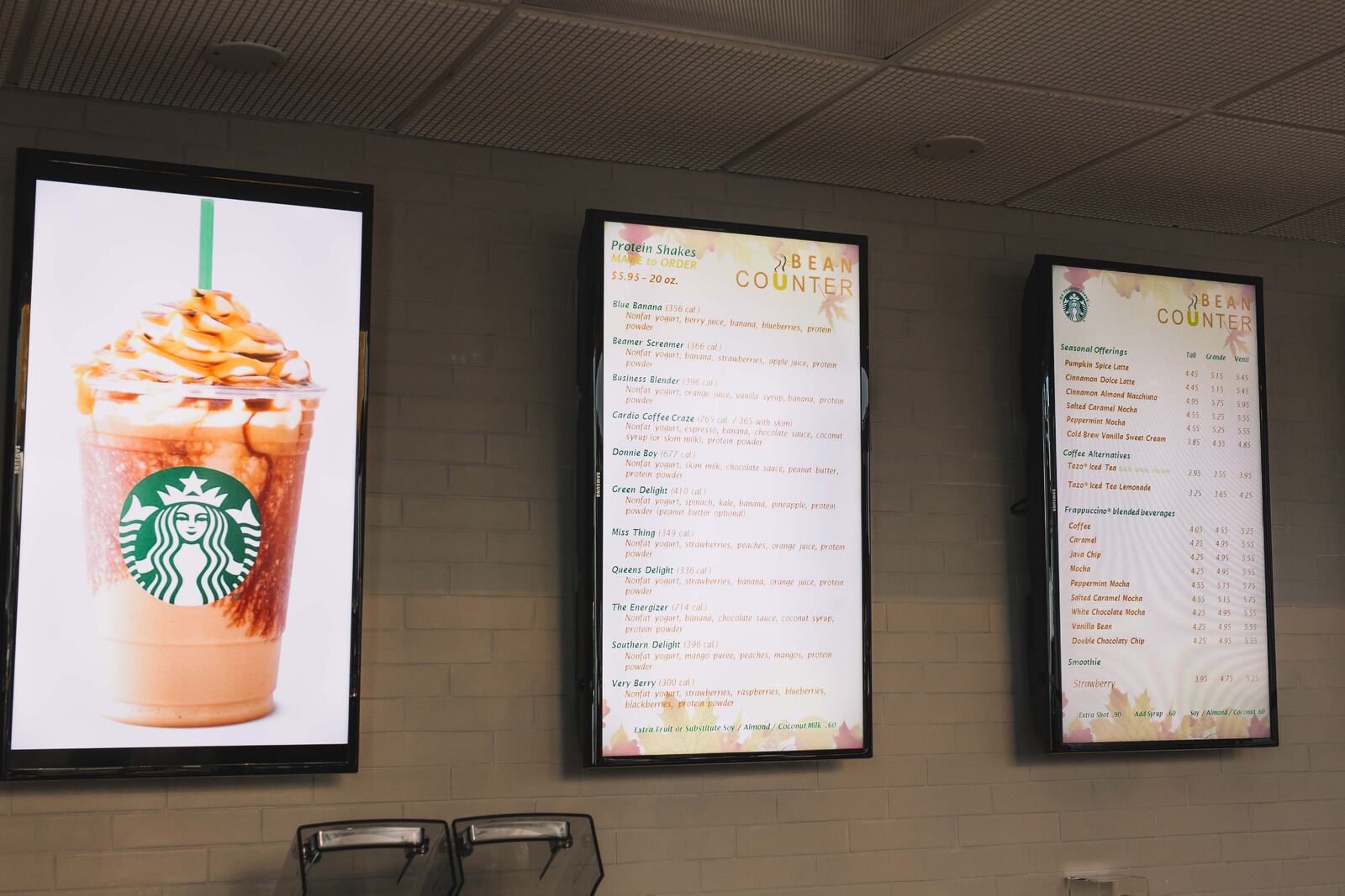 Digital menu boards listing the protein shakes and Starbucks drinks